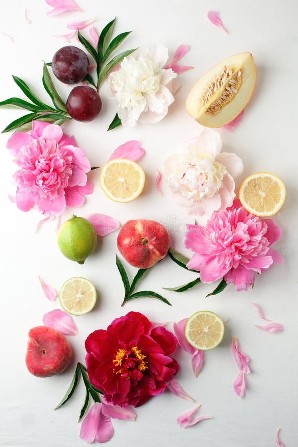 Colorful food pattern made of lemon, melon, plum, peach, grapefruit and beautiful peoniy flowers. Flat lay.