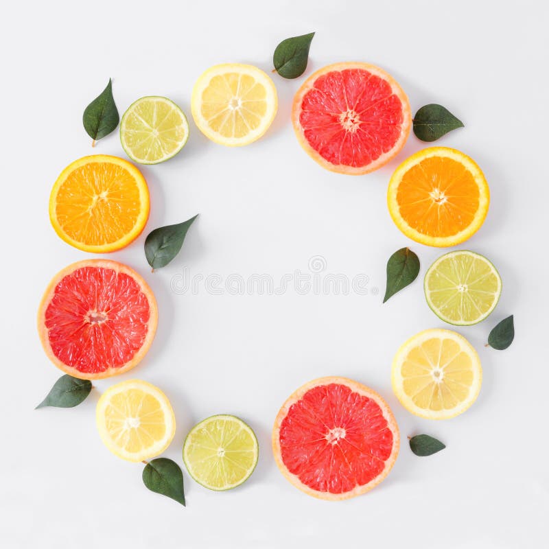 Colorful fruit circle frame of citrus slices and leaves, top view over a white background stock photography