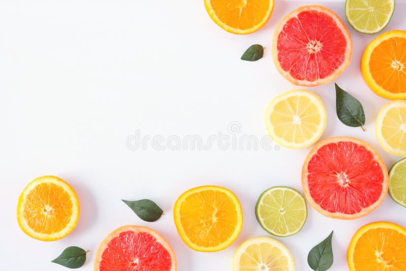 Colorful fruit corner border of citrus slices and leaves, top view over a white background stock photo