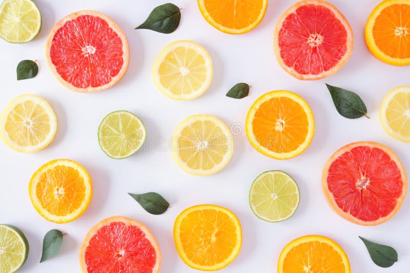Colorful fruit pattern of citrus slices and leaves, top view over a white background stock image