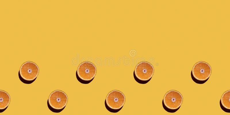 Colorful fruit seamless pattern of halves of oranges on a yellow background. Top view, copy space.