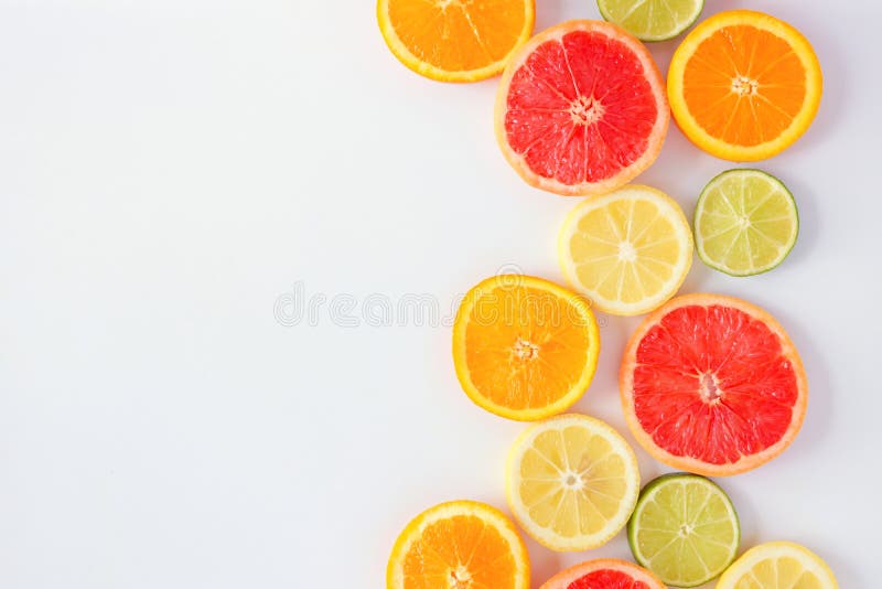 Colorful fruit side border of citrus slices, top view over a white background stock images