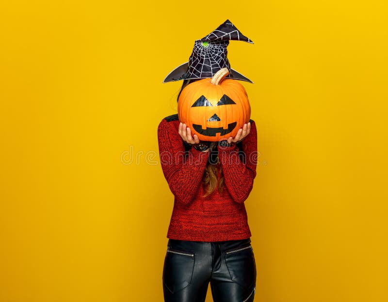 Woman holding sad jack-o-lantern pumpkin in front of face