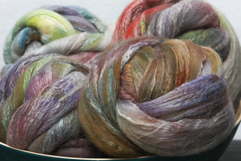 Colorful, handdyed roving of sheepwool, rolled up, natural material ready for spinning on a traditional spinning wheel as a hobby. royalty free stock images