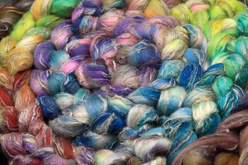Colorful, handdyed roving of sheepwool, rolled up, natural material ready for spinning on a traditional spinning wheel as a hobby. stock image