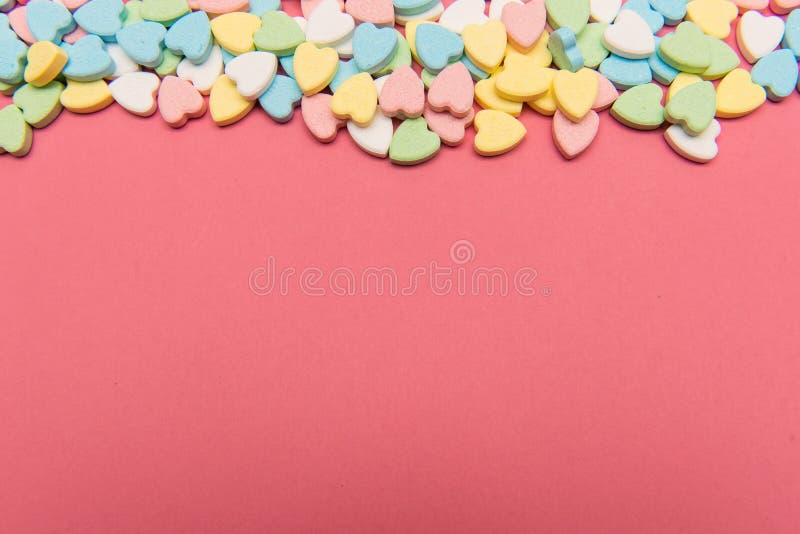 Colorful heart shaped candy on top of pink surface , valentine`s day love concept with copy space