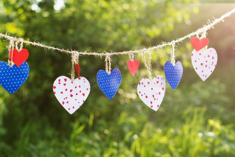 Colorful textured hearts hanging on green grass background. Colorful textured hearts hanging on green grass background