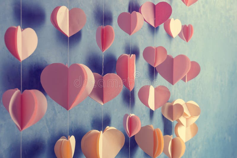 Colorful hearts paper garland hanging on the wall. Romantic Valentine's day background. Instagram style toned photo with copy space for your text
