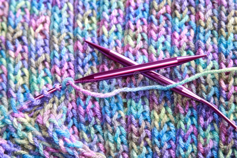 Close up photo of a hand made work in progress on a colorful scarf being knit in a rib stitch pattern on circular knitting needles. Close up photo of a hand made work in progress on a colorful scarf being knit in a rib stitch pattern on circular knitting needles.