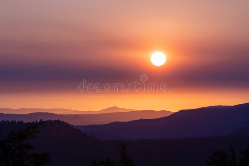 Colorful Layers of Clouds and Forest Below Dimmed Sun In The Clouds royalty free stock photo
