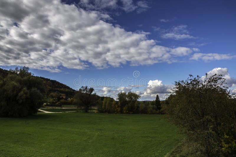 Colorful leaves, green meadows, and the cloudy blue sky royalty free stock photography