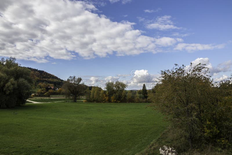 Colorful leaves, green meadows, and the cloudy blue sky stock photo