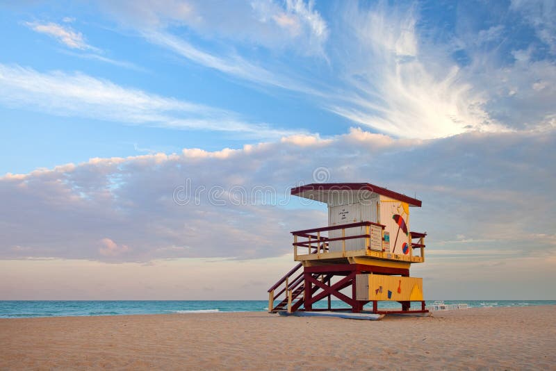 Summer scene in Miami Beach Florida, with a colorful lifeguard house in a typical Art Deco architecture, at sunset with ocean and sky in the background. Summer scene in Miami Beach Florida, with a colorful lifeguard house in a typical Art Deco architecture, at sunset with ocean and sky in the background.