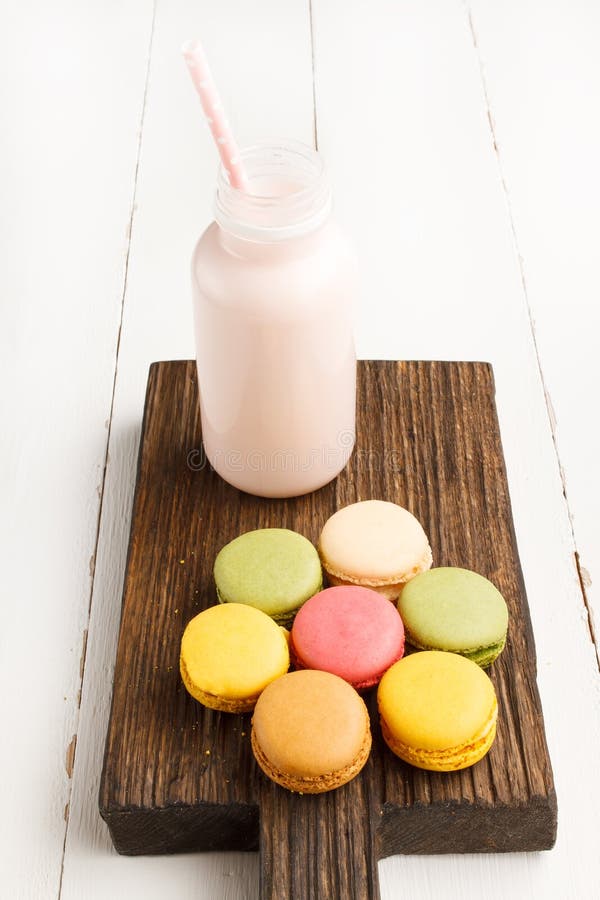 Colorful macaroons and bottle of milk on vintage cutting board