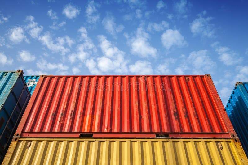 Colorful metal Industrial cargo containers are stacked in the storage area under blue cloudy sky. Colorful metal Industrial cargo containers are stacked in the storage area under blue cloudy sky
