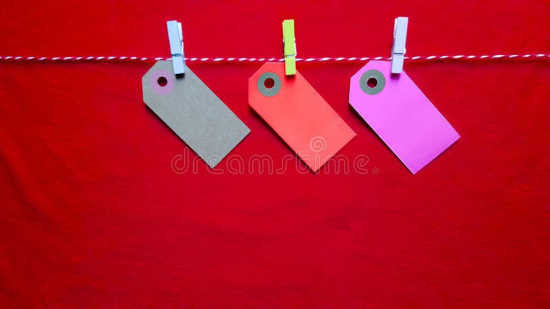 Colorful paper notes and clothespins on a red background. Empty color cardboard price tags, sale tag, gift tag, address label