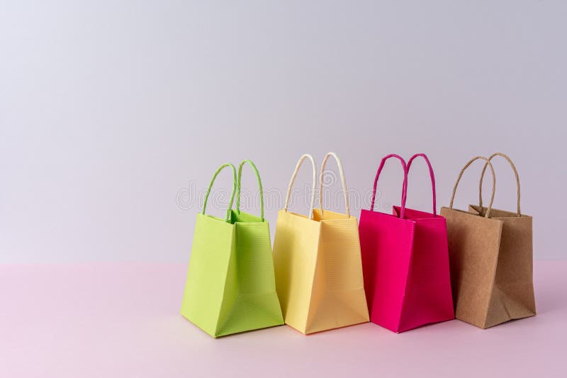 Colorful paper shopping bags on bright background. Creative minimal shopping concept