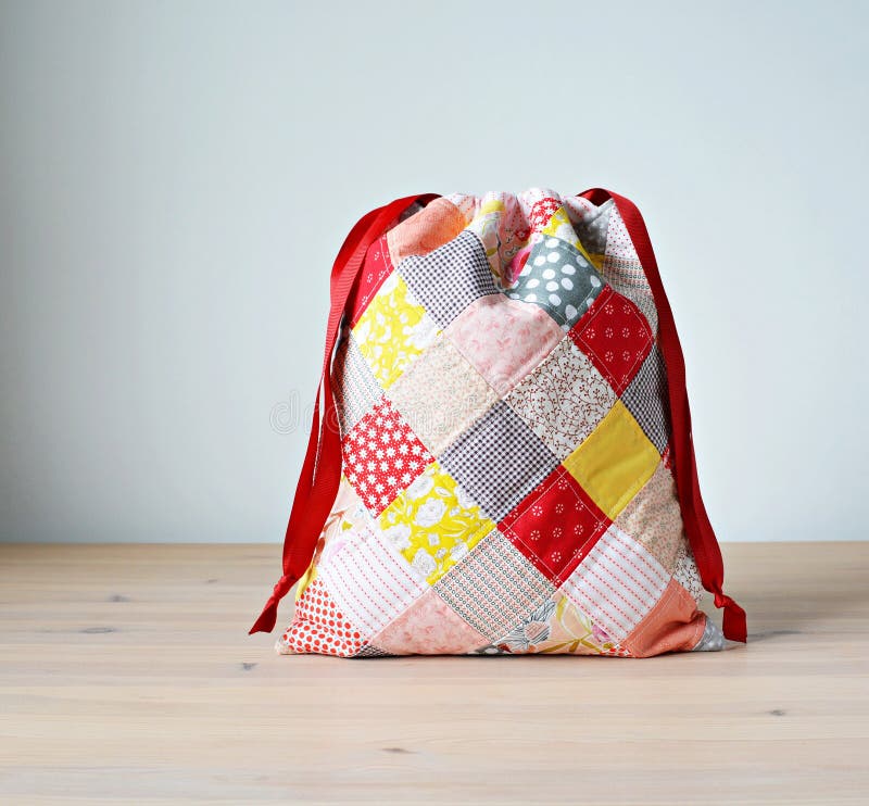 Colorful patchwork drawstring bag on wooden table stock image
