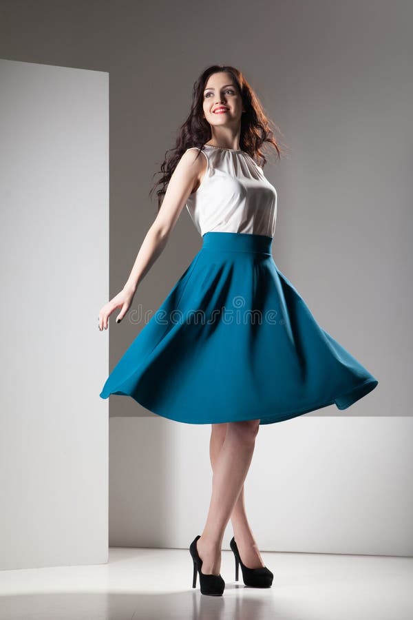 Colorful photo of a woman in white top and dark blue skirt wearing high hells shoes. Isolated on grey and white background.
