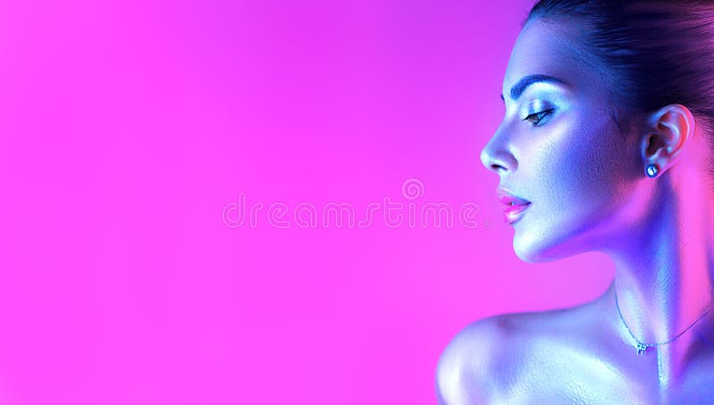 Colorful portrait of a beautiful young woman over purple background. High Fashion model girl in colorful bright neon lights