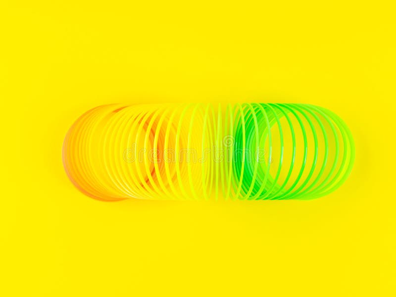 Colorful rainbow spiral plastic toy on yellow background