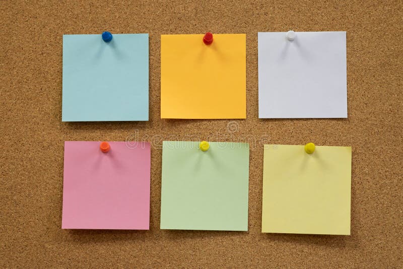 Colorful reminder sticky notes push pins on cork board. Empty free space