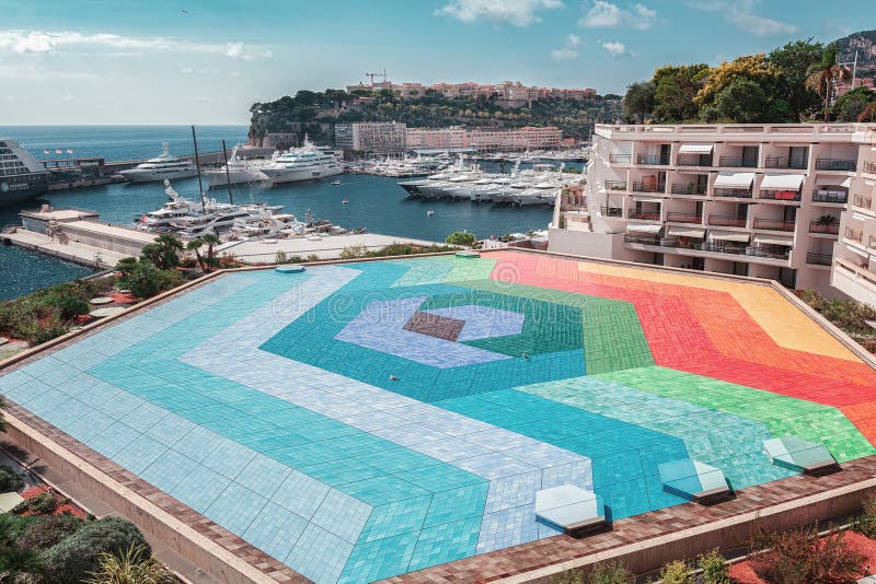 The colorful roof of the Rainier III auditorium with a the port Hercule of Monaco in the background stock photo The colorful roof of the Rainier III auditorium with a the port Hercule of Monaco in the background stock photo