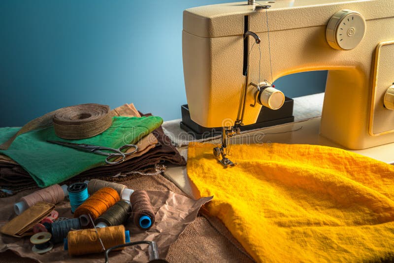 Colorful sewing background with sewing machine and accessories on blue background. royalty free stock image