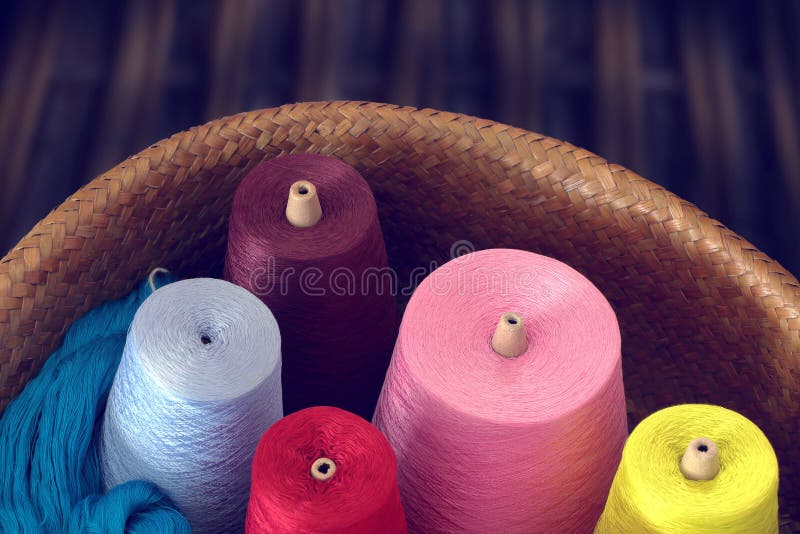 Colorful spools of thread in a wicker basket. vintage tone