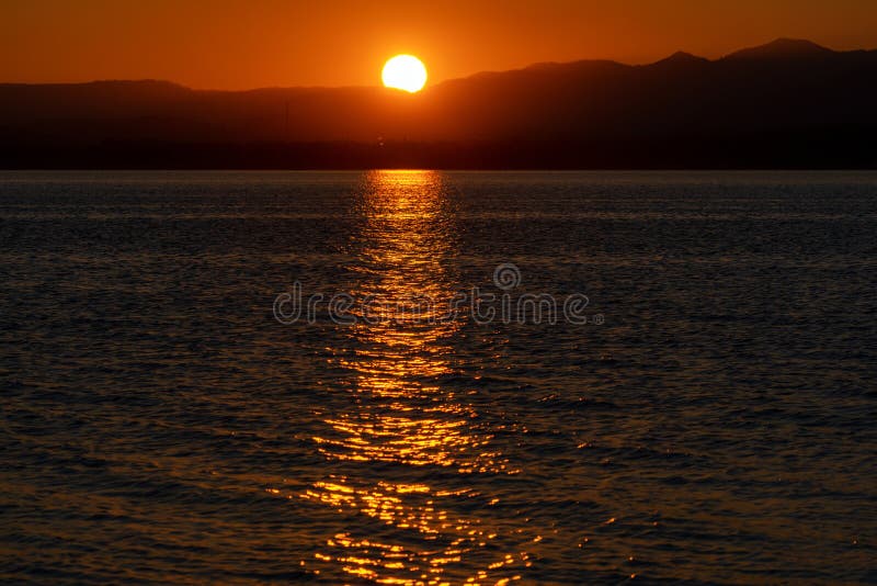 Farebná krajina pri východe slnka. Veľké slnko na oranžovej oblohe nad siluetou hôr. Jazero Liptovská Mara, Slovensko