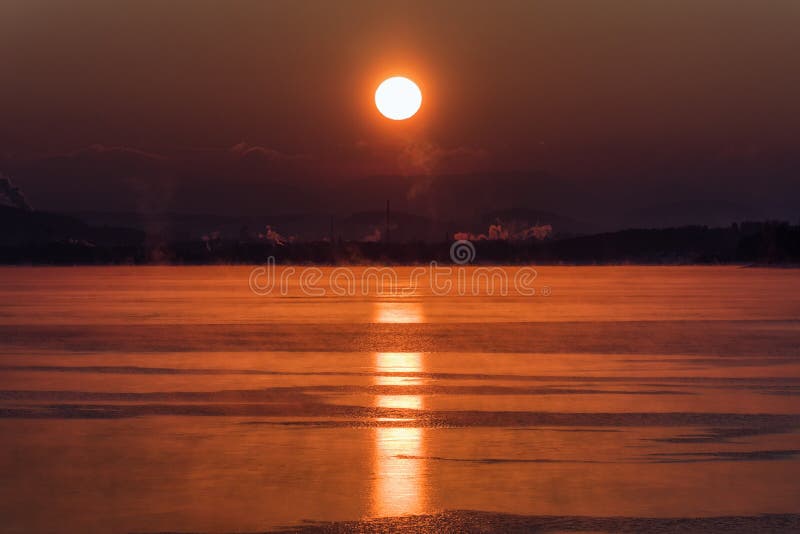 Farebný východ slnka nad jazerom a komínmi
