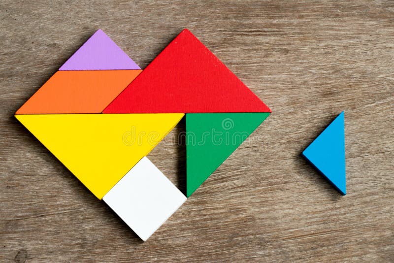 Colorful tangram puzzle in heart shape wait to fulfill on wood background Concept of happy family, love fulfillment