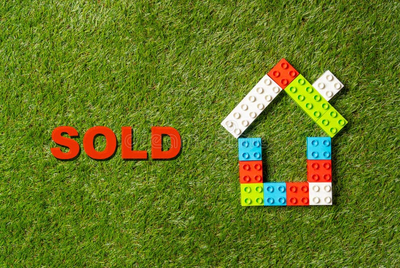 Colorful toy blocks house word Sold written on grass in Real State and Property industry concept