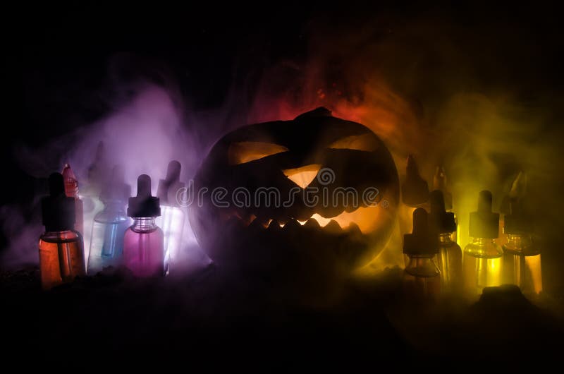 Colorful vape liquids with Halloween pumkin on dark background. Vape concept