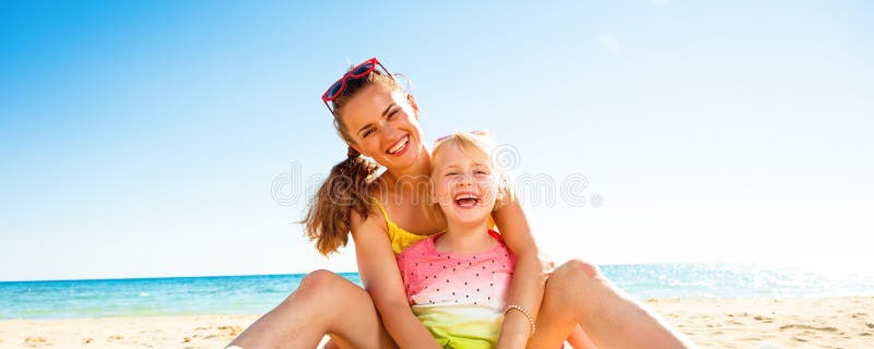 Happy trendy mother and daughter sitting on beach royalty free stock image Happy trendy mother and daughter sitting on beach royalty free stock image