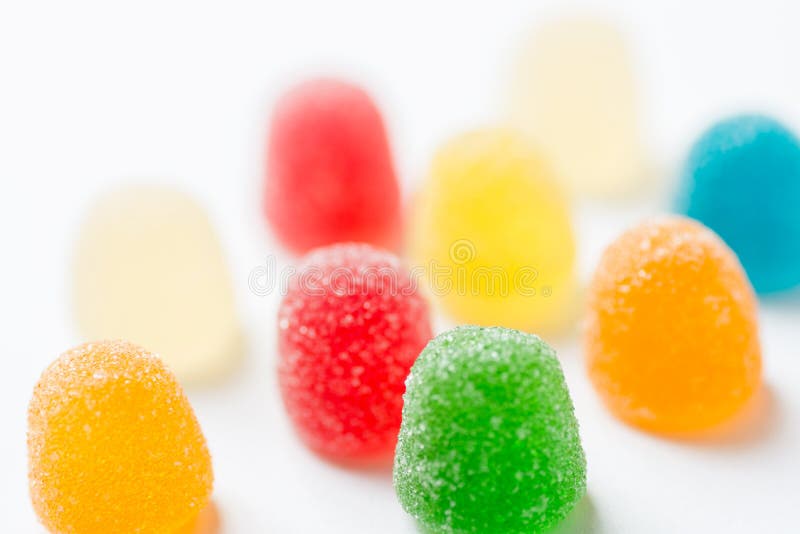 Colorful yellow red orange green gummy jelly candies coated with sugar on white background. Kids birthday party sweets fun