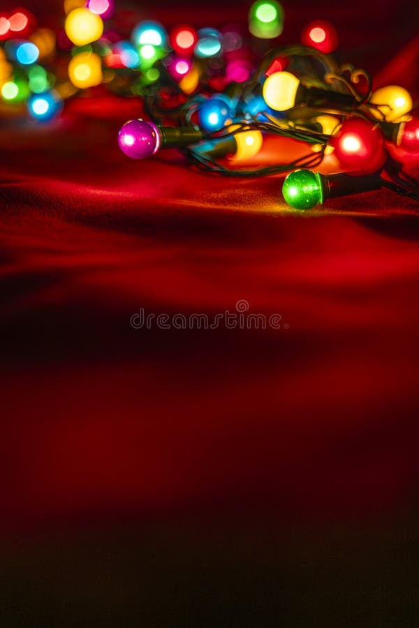 Colourful Christmas lights on soft red fabric. Selective focus. stock photos