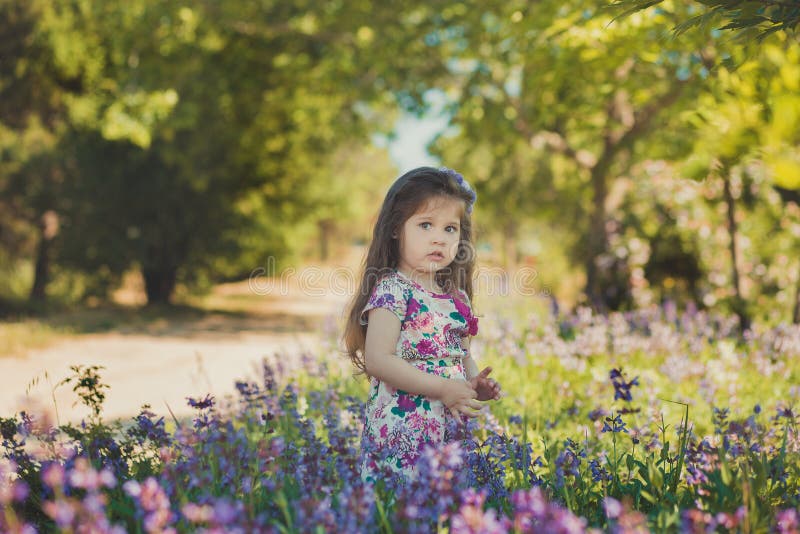 Colourful summer scene of cute runette young girl child enjoying free time in wild forest flowers field wearing stylish tiny dress. Fashionable, bespoke.