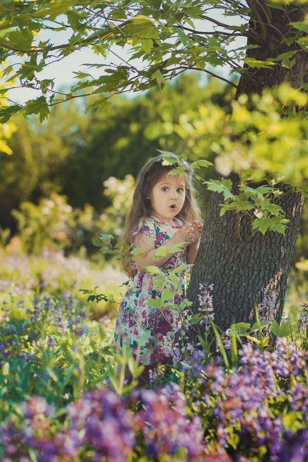 Colourful summer scene of cute runette young girl child enjoying free time in wild forest flowers field wearing stylish tiny dress. Contemporary, adore.