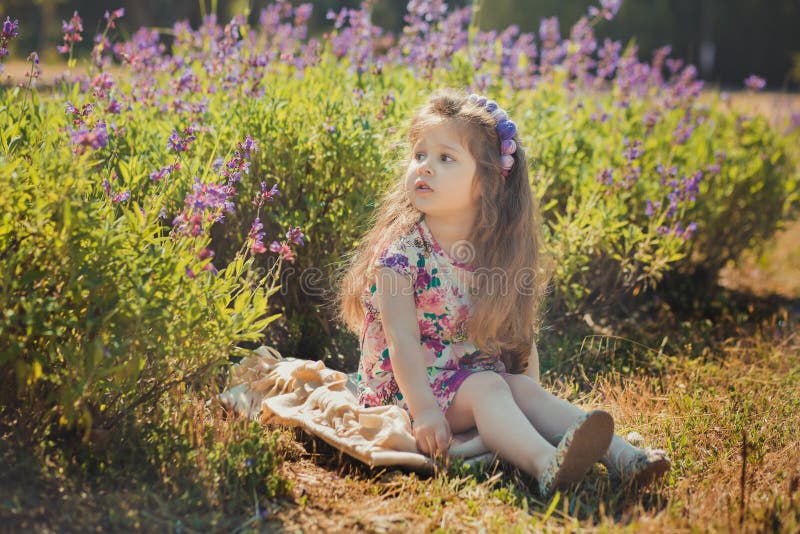 Colourful summer scene of cute runette young girl child enjoying free time in wild forest flowers field wearing stylish tiny dress. Fancy, adore.