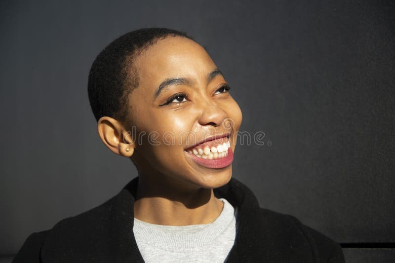 Colpo del fronte del ritratto di sorriso della donna africana della testa teenager della pelle 20s con il fondo nero grigio della fotografie stock libere da diritti Colpo del fronte del ritratto di sorriso della donna africana della testa teenager della pelle 20s con il fondo nero grigio della fotografie stock libere da diritti