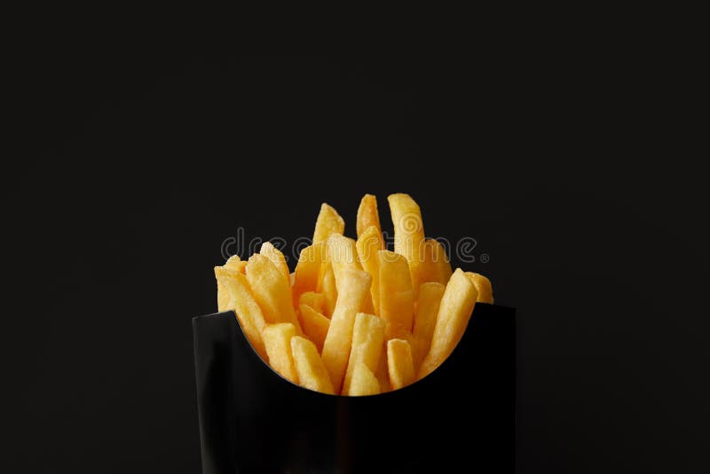colpo del primo piano della scatola nera delle patate fritte deliziose isolate sul nero immagini stock libere da diritti colpo del primo piano della scatola nera delle patate fritte deliziose isolate sul nero immagini stock libere da diritti