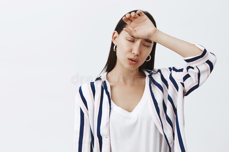 Colpo dell'interno della donna sveglia stanca e triste in blusa d'avanguardia a strisce, tenente braccio sulla fronte e espirante fotografie stock libere da diritti Colpo dell'interno della donna sveglia stanca e triste in blusa d'avanguardia a strisce, tenente braccio sulla fronte e espirante fotografie stock libere da diritti