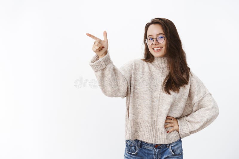 Colpo dell'interno della femmina attraente spensierata felice in vetri e mano della tenuta del maglione sulla vita, sorridente e fotografie stock Colpo dell'interno della femmina attraente spensierata felice in vetri e mano della tenuta del maglione sulla vita, sorridente e fotografie stock