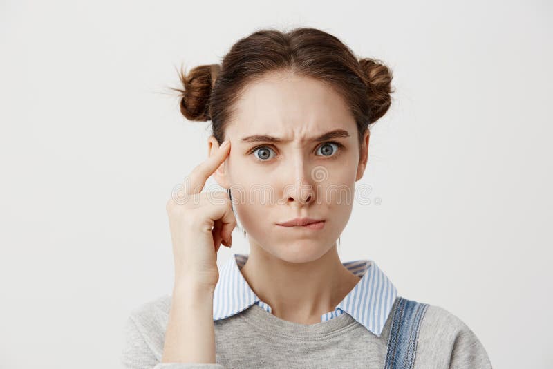 Colpo dello studio della donna caucasica premurosa in dito casuale della tenuta al suo tempio che posa con lo sguardo significati fotografia stock Colpo dello studio della donna caucasica premurosa in dito casuale della tenuta al suo tempio che posa con lo sguardo significati fotografia stock