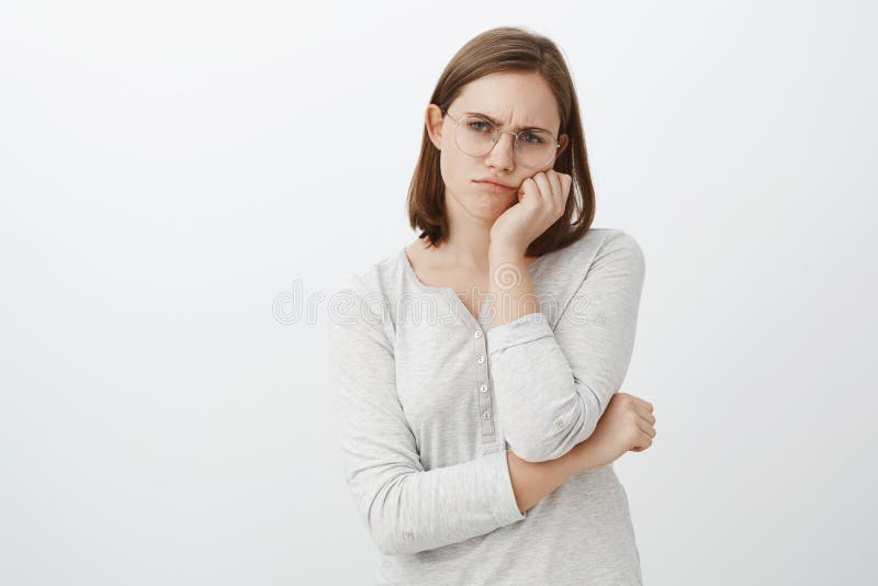 Colpo dello studio della giovane donna sveglia dispiaciuta ed infelice sola in vetri con brevi capelli marroni che aggrotta le so fotografia stock libera da diritti Colpo dello studio della giovane donna sveglia dispiaciuta ed infelice sola in vetri con brevi capelli marroni che aggrotta le so fotografia stock libera da diritti
