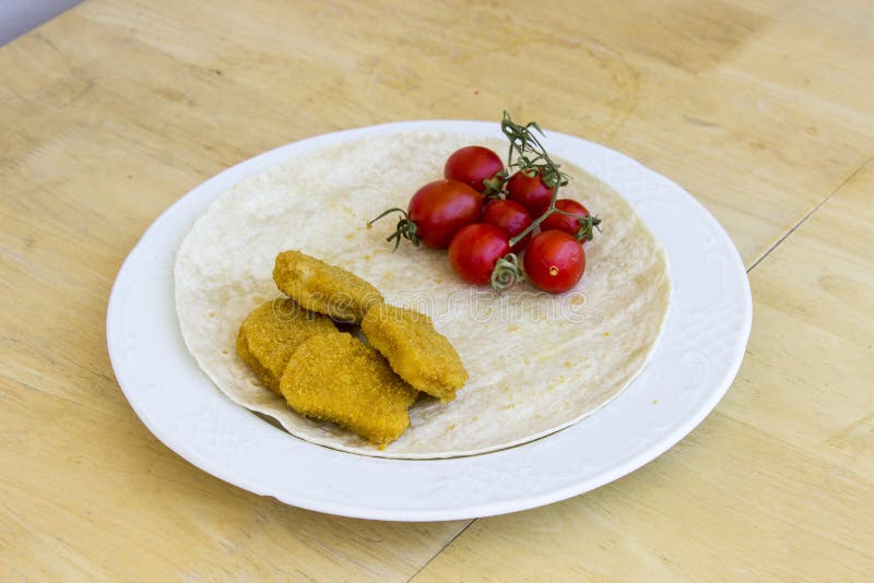 Colpo di prospettiva delle pepite di pollo cucinate e di piccoli pomodori freschi rossi sull'ampio piatto bianco come prima colaz fotografie stock Colpo di prospettiva delle pepite di pollo cucinate e di piccoli pomodori freschi rossi sull'ampio piatto bianco come prima colaz fotografie stock