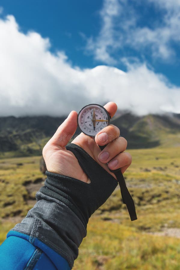 Colpo di punto di vista Una vista in prima persona di una mano del ` s dell'uomo tiene una bussola contro lo sfondo di un paesagg fotografie stock libere da diritti Colpo di punto di vista Una vista in prima persona di una mano del ` s dell'uomo tiene una bussola contro lo sfondo di un paesagg fotografie stock libere da diritti