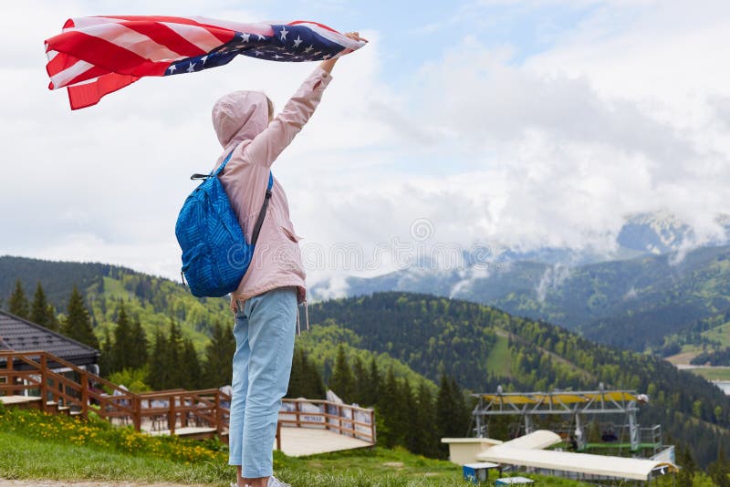 Colpo integrale di profilo di bella giovane donna con la bandiera americana tenuta nella sua condizione della mano tesa davanti a immagini stock Colpo integrale di profilo di bella giovane donna con la bandiera americana tenuta nella sua condizione della mano tesa davanti a immagini stock