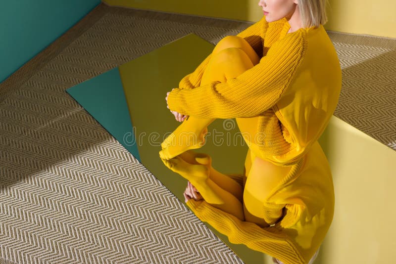 colpo potato della donna in maglione giallo e calzamaglia che si siedono sullo specchio con la riflessione fotografia stock colpo potato della donna in maglione giallo e calzamaglia che si siedono sullo specchio con la riflessione fotografia stock